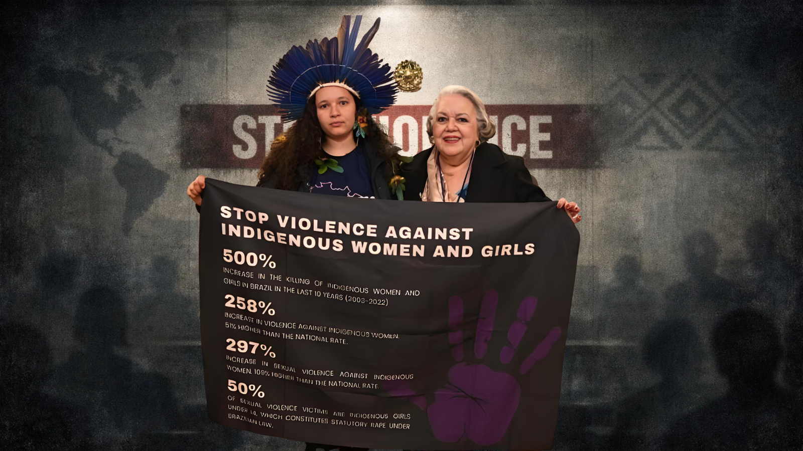 Jovem mulher indígena com cocar tradicional segura faixa denunciando a violência contra mulheres indígenas durante evento internacional.